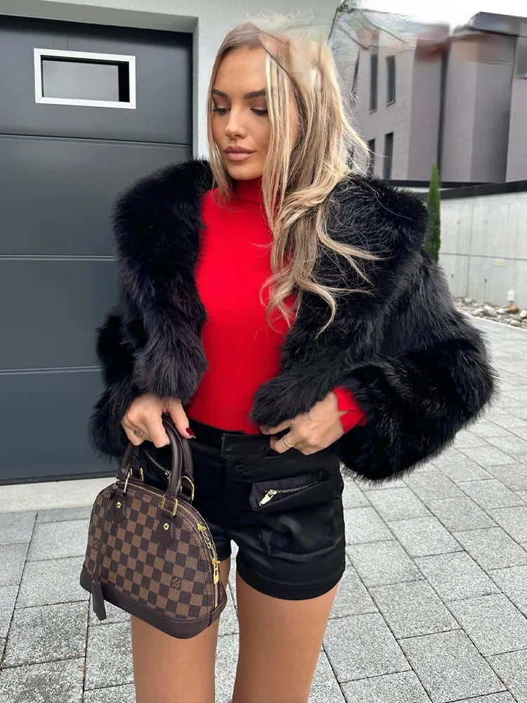 Stylish woman in red top wearing an artificial fur cropped winter coat with black shorts and designer handbag