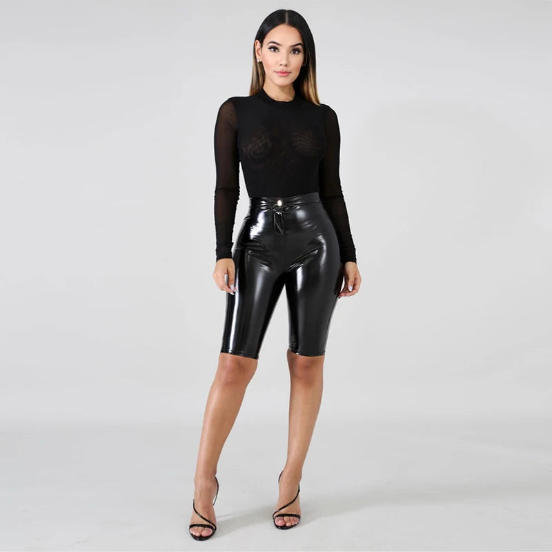 Model wearing patent leather bicycle shorts paired with a sheer black top for a stylish look