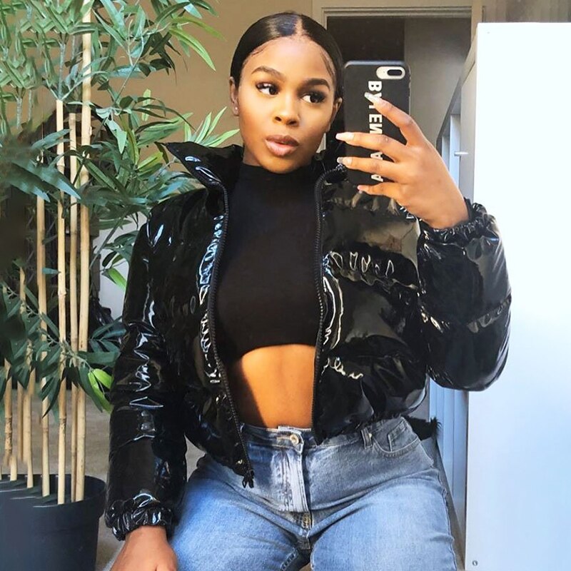 Stylish woman wearing a cropped shiny puffer coat paired with high-waisted jeans