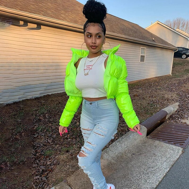 Trendy cropped shiny puffer coat in vibrant neon green paired with distressed jeans