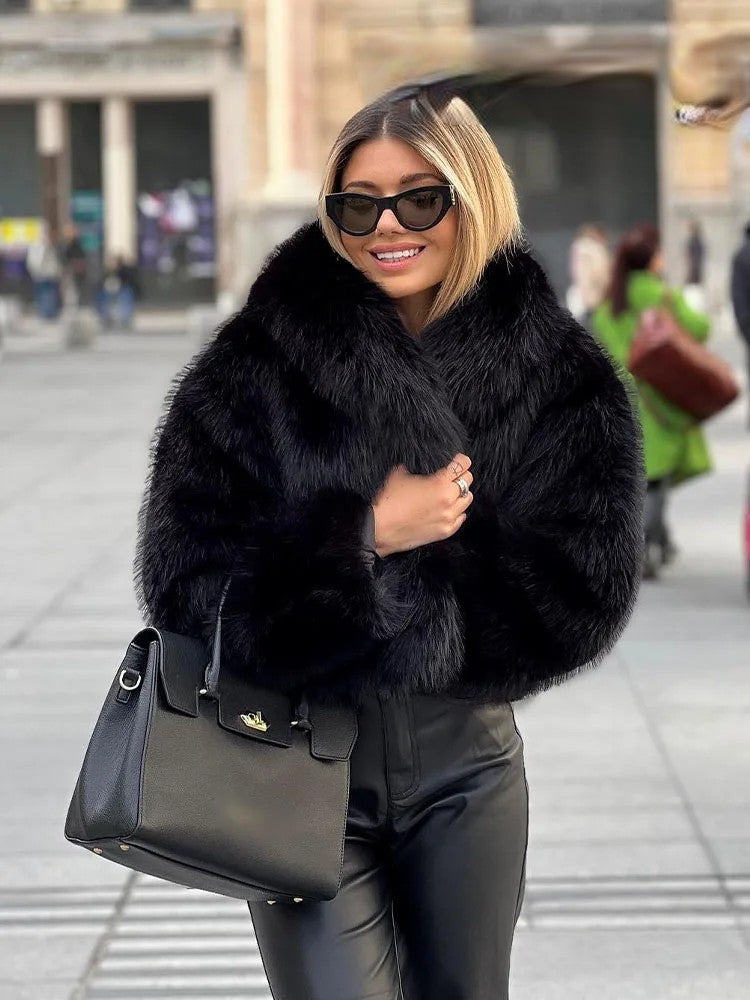Stylish woman wearing an artificial fur cropped winter coat with a black handbag on a city street