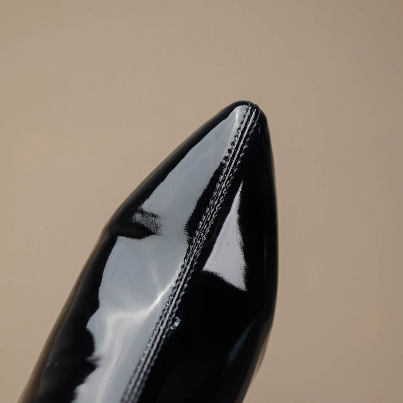 Close-up of glossy over the knee leather boots showcasing pointed toe design