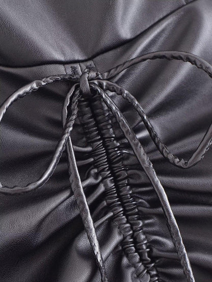 Close-up of the drawstring faux leather dress showcasing the tied detail and ruched fabric design